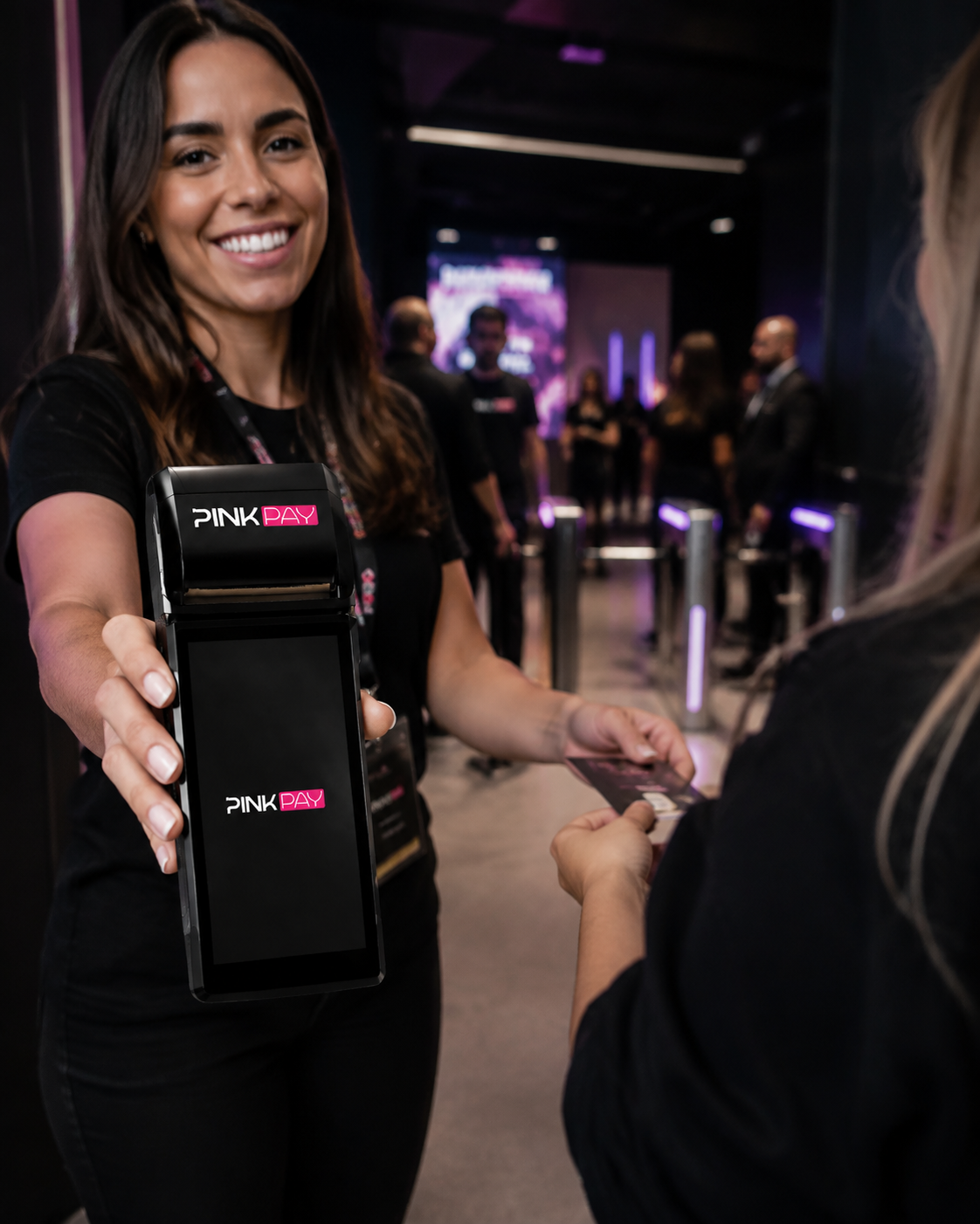 Atendente Pink Pay entregando a maquininha para uma cliente pagar com cartão